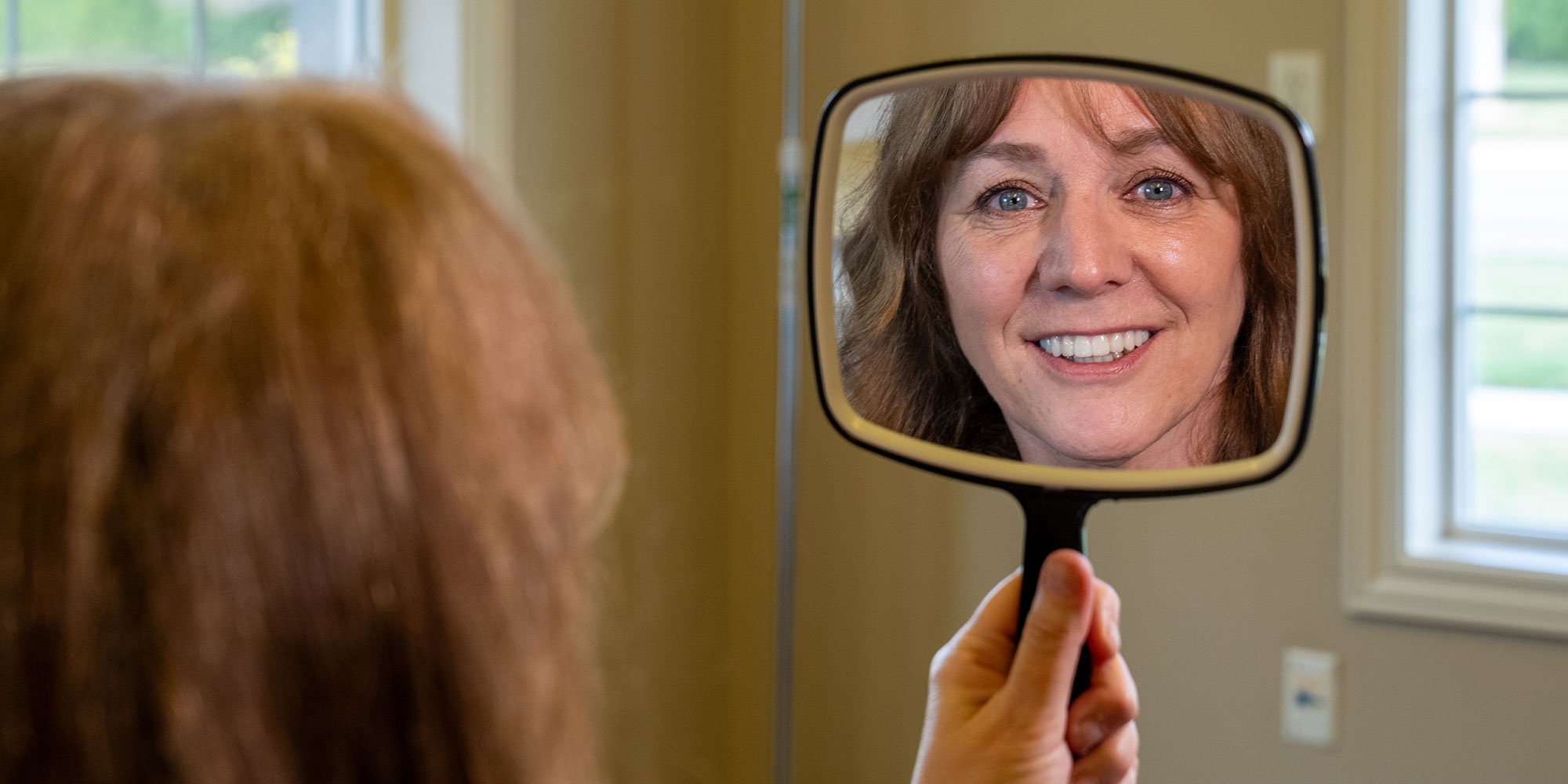 patient looking into a mirror looking at their new smile