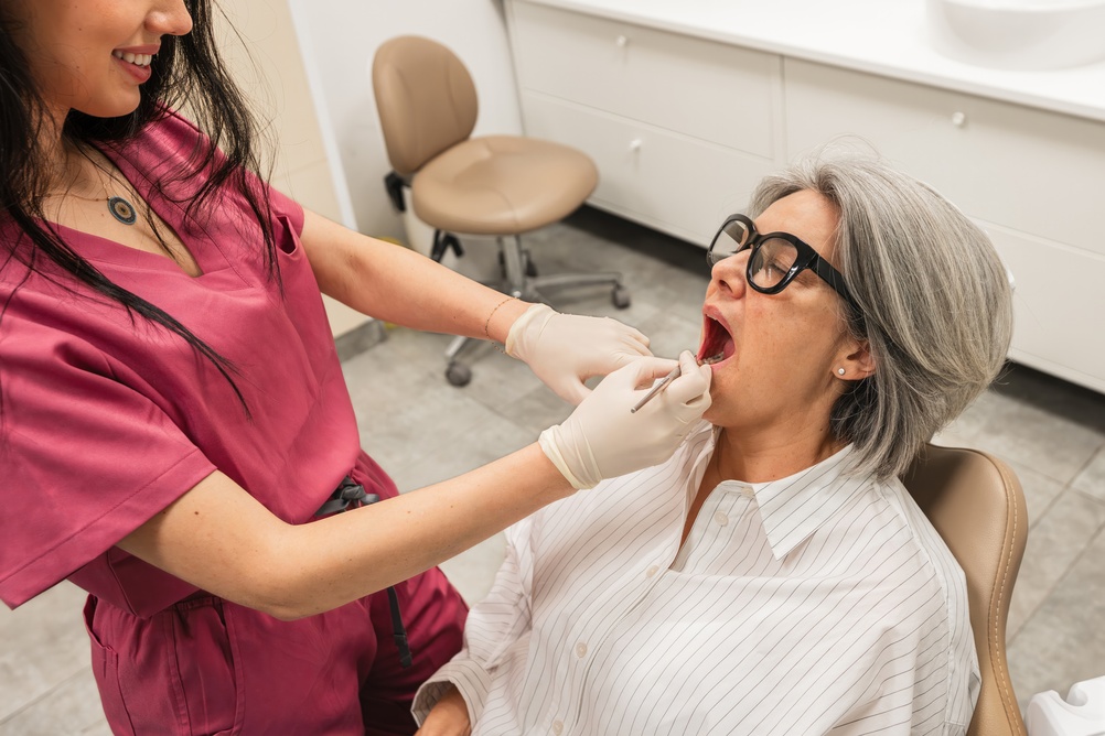 Close up view of a dentist using specialized tools to perform a gum grafting procedure to restore receding gums, focus on the precision and delicate nature of the work. No text on image.